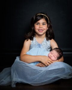 sisters in matching blue at a newborn photo shoot