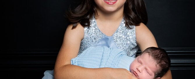sisters in matching blue at a newborn photo shoot