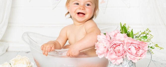 a little girl in a milk bath with flowers and a love sign at a professional photo shot