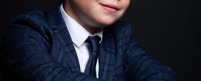 a young man poses in a suit and tie for a professional photo shoot