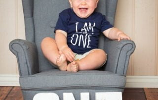 a very happy one year old boy giggles for the camera