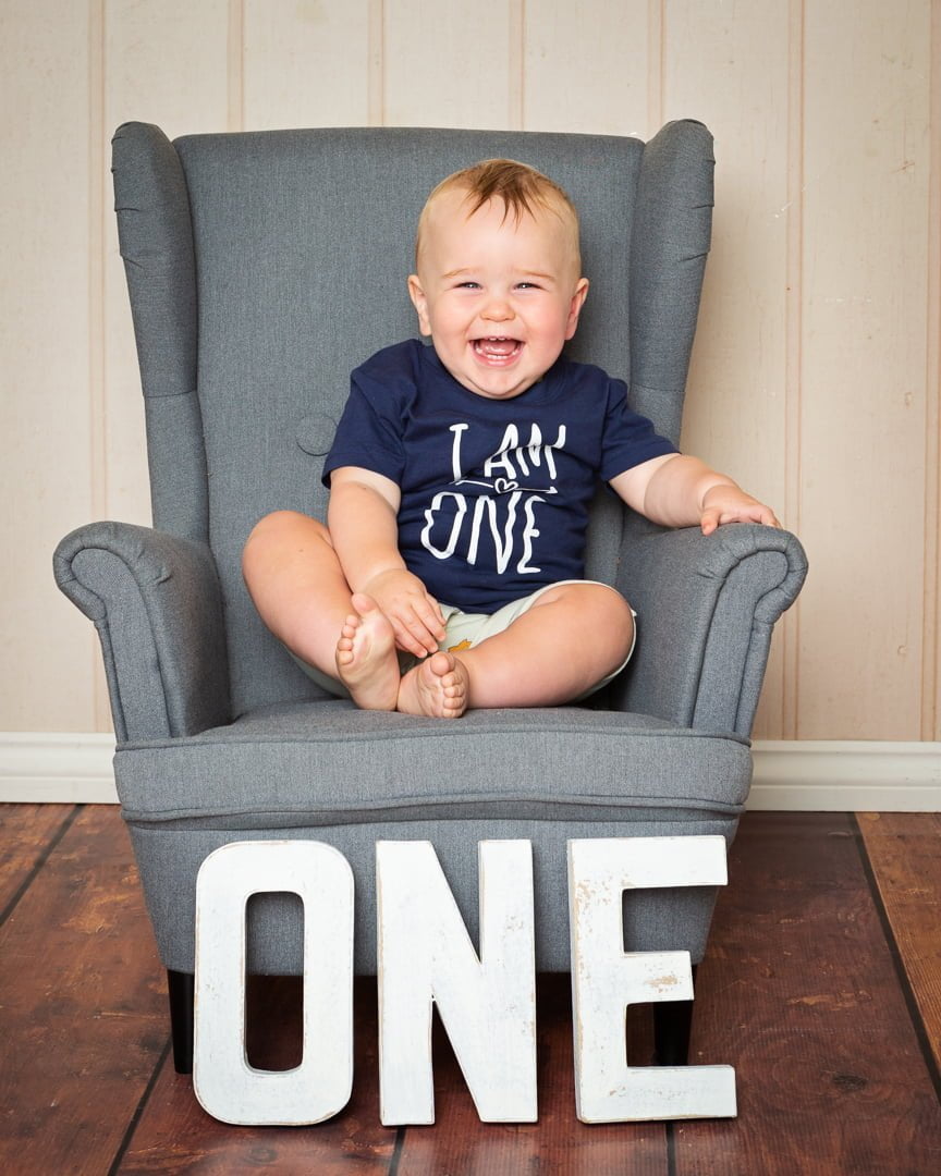 a very happy one year old boy giggles for the camera