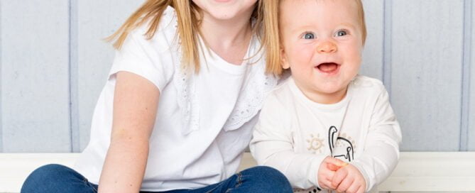 a brother and sister pose together in jeans and matching shirts.