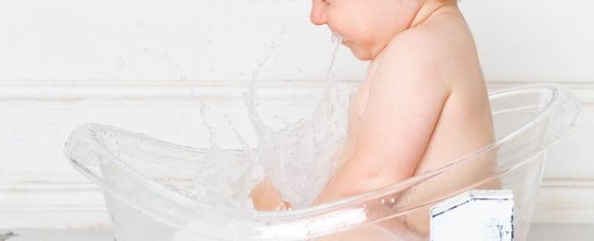 a little boy splashing in a milk bath at his first birthday photo shoot
