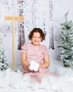 Christmas Photo Shoot Event West Sussex a little girl holds a pile of snowballs in a snow christmas photo shoot set