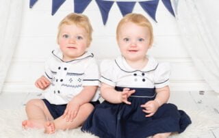 Twins pose in matching navy and white outfits