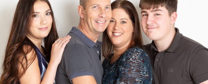 A mum, dad and their two adult children posing against a white background