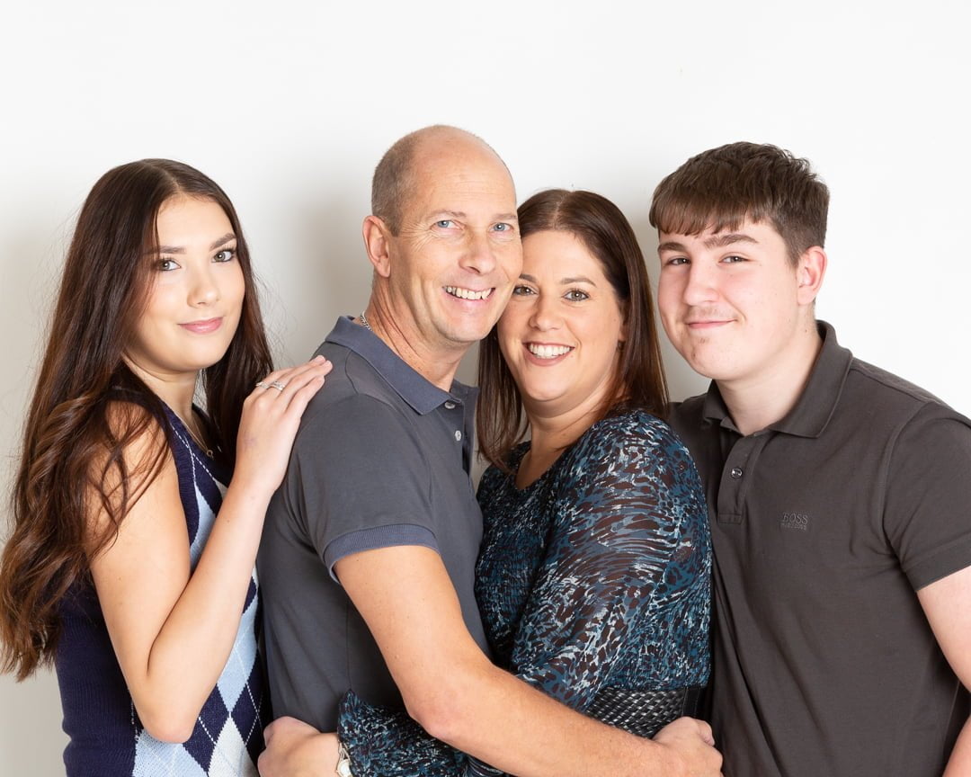 A mum, dad and their two adult children posing against a white background