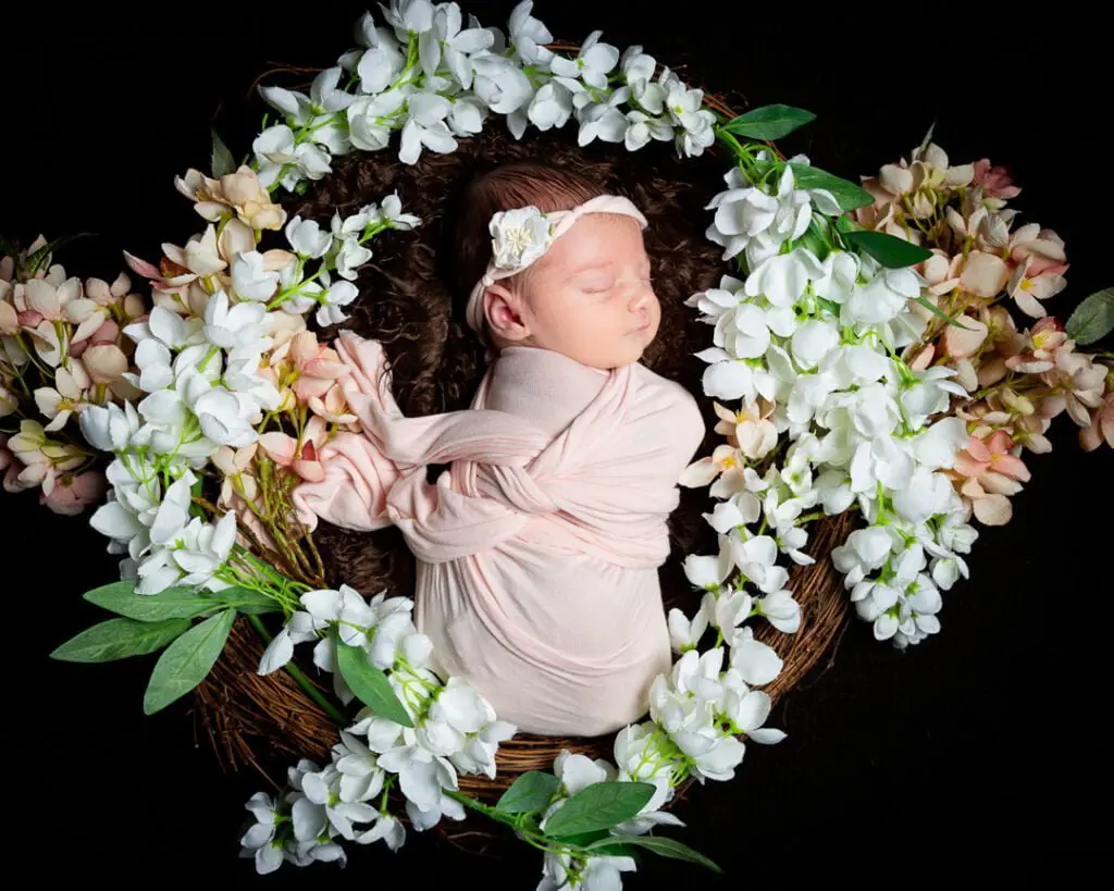 a little girl sleeps in a nest of peach and white flowers