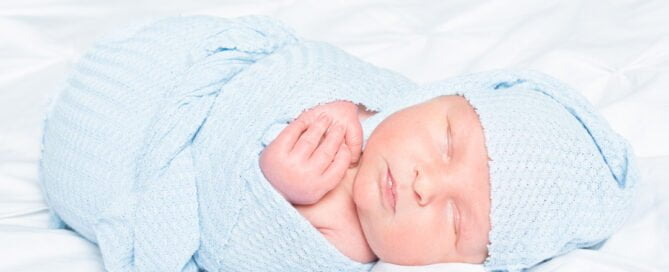 a baby wrapped in pale blue with a matching hat