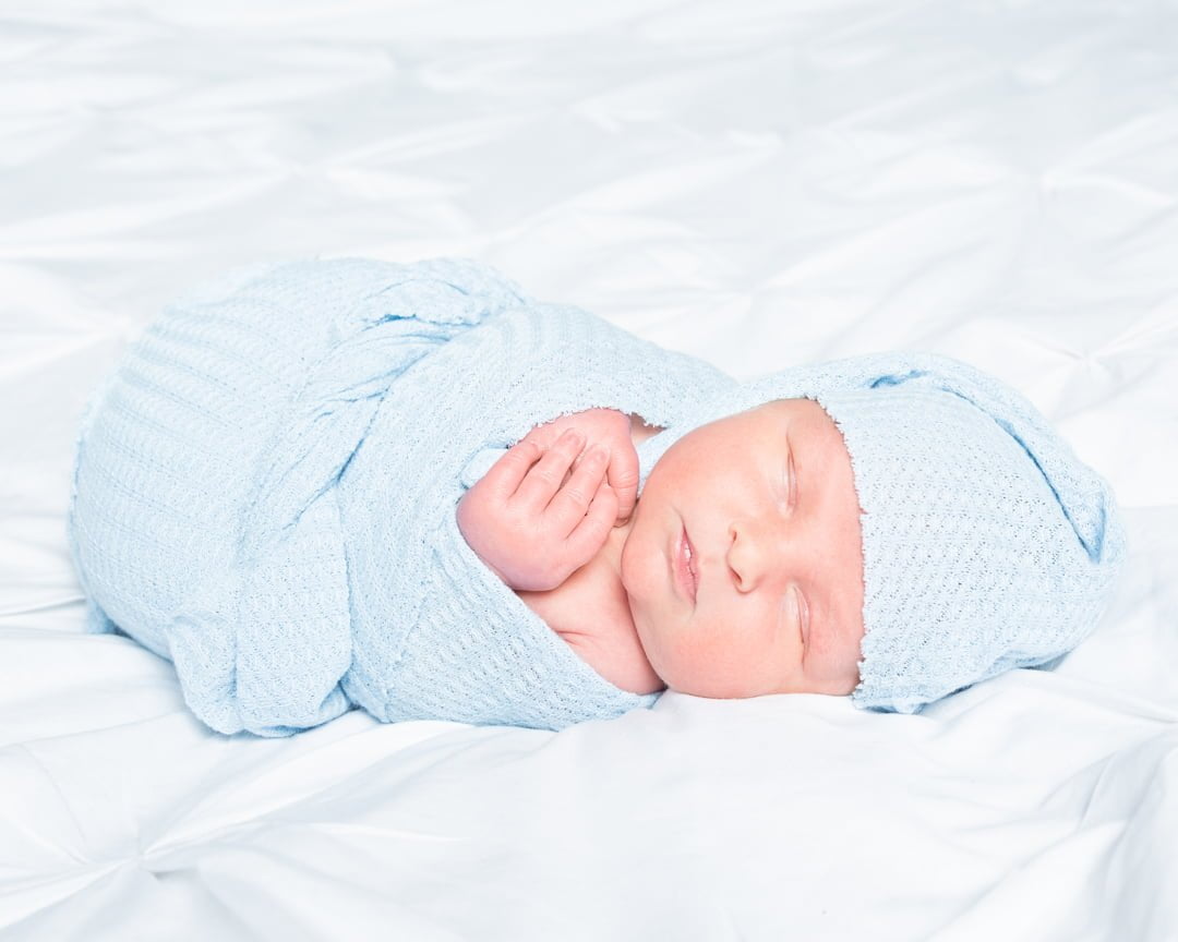 a baby wrapped in pale blue with a matching hat