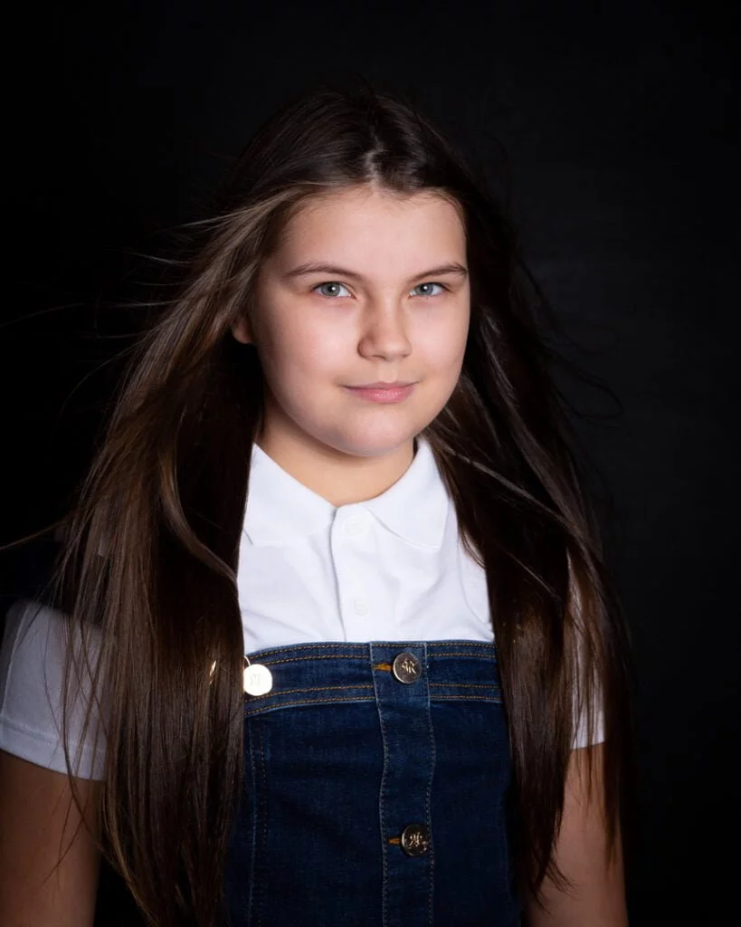 a girl poses in the studio with the wind machine moving her hair