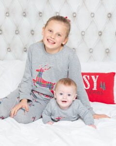 Silbings pose on a bed in matching pjs