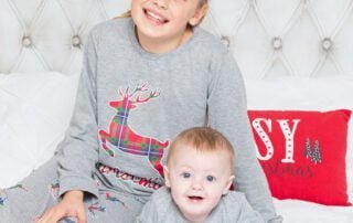 Silbings pose on a bed in matching pjs