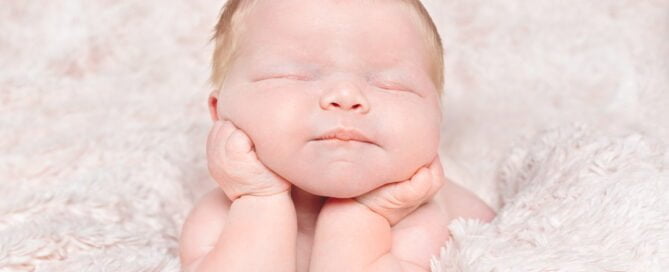 a digitally composited image of a sleeping newborn with their head in their hands