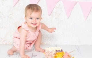 A baby in a superhero landing pose by a cake a professional photo shoot