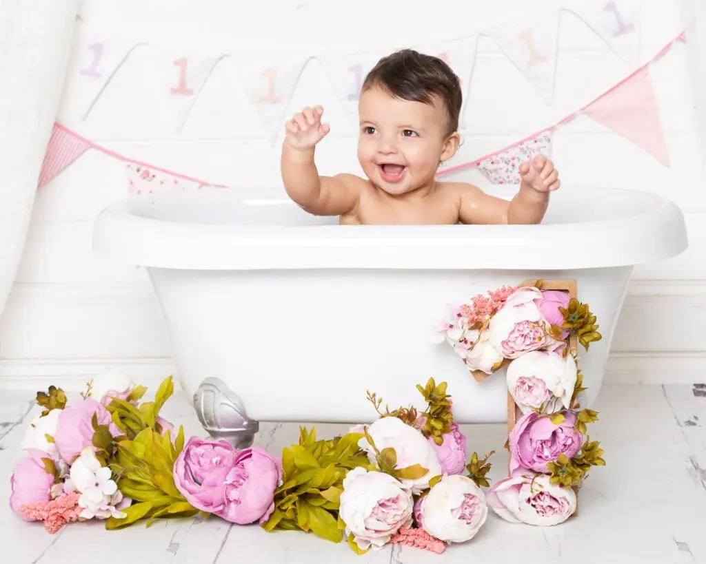an excited little girl is enjoying playing in the water at her tub splash photo shoot