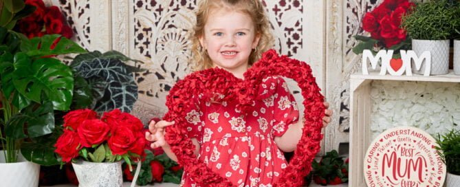 a little girl holds a heart made of roses at a mother's day photo shoot