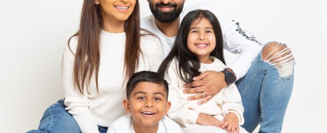 A family of mum, dad and two children all wearing blue jeans and white tops