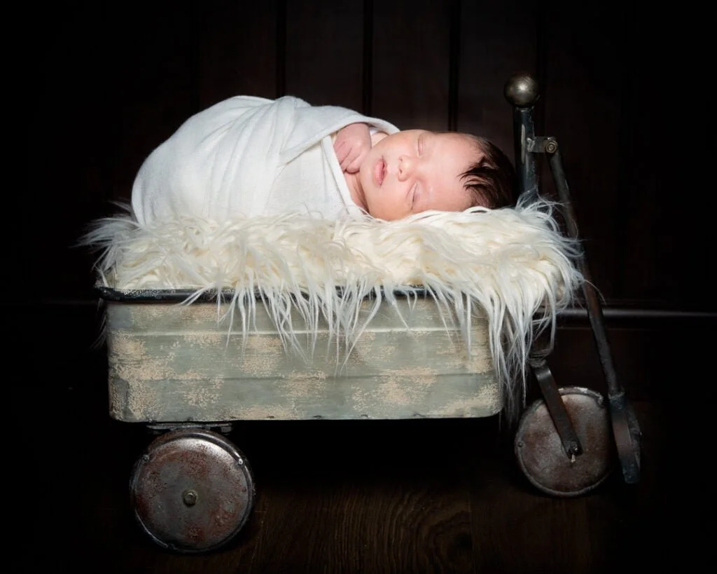 a sleeping newborn on a vintage metal trolley