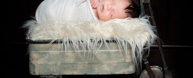 a sleeping newborn on a vintage metal trolley