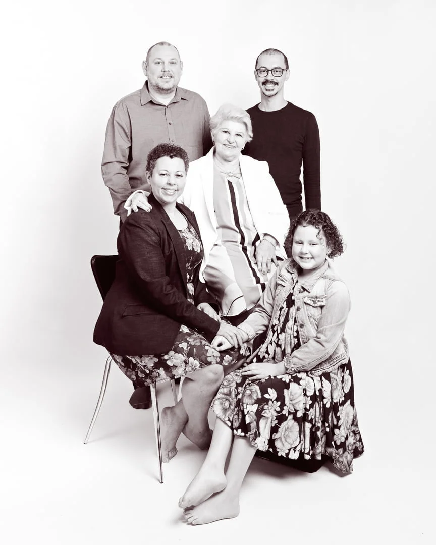 Three generations of family posing for a studio family portrait