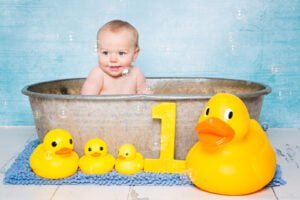 a little baby in a bathtub surrounded by bubbles and rubber ducks