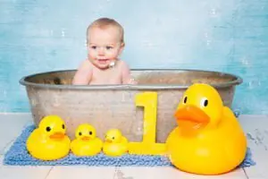 Baby Photography in East Grinstead West Sussex a little baby in a bathtub surrounded by bubbles and rubber ducks