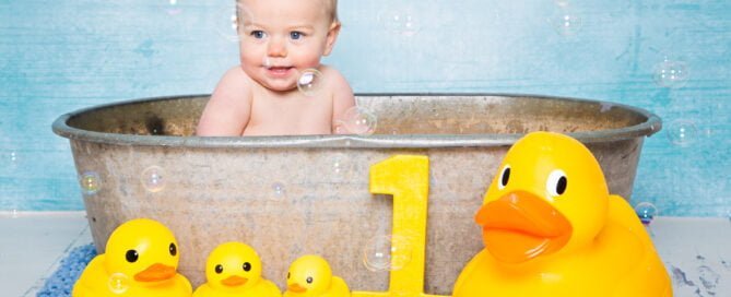 a little baby in a bathtub surrounded by bubbles and rubber ducks