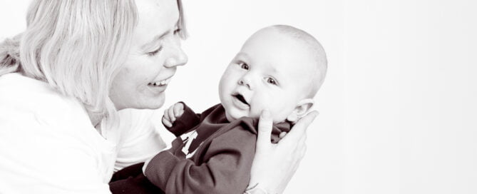 A black and white image of a mum holding her baby and looking at him