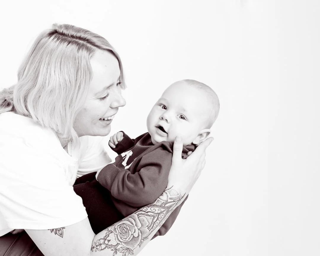 A black and white image of a mum holding her baby and looking at him