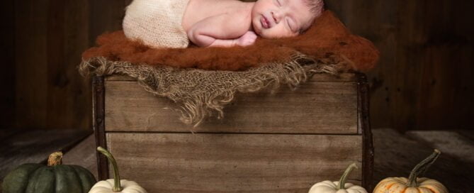a newborn sleeping on a digital pumpkin crate