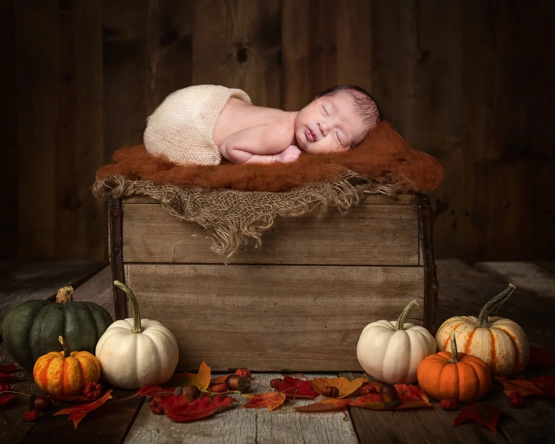 a newborn sleeping on a digital pumpkin crate