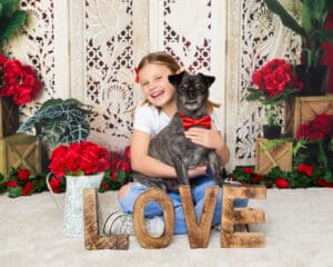 Portrait Photography West Sussex a girl poses with her dog in a red bow tie