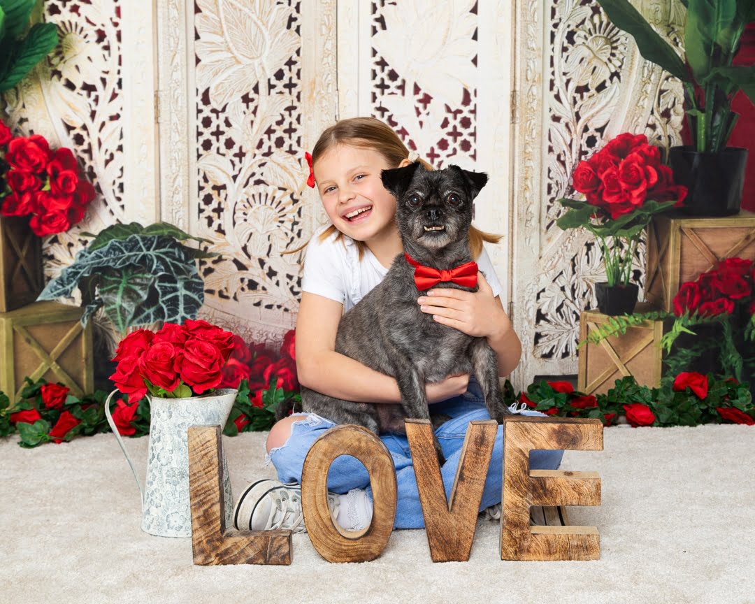 a girl poses with her dog in a red bow tie