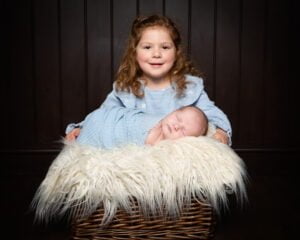 a newborn and big sister in matching shades of blue