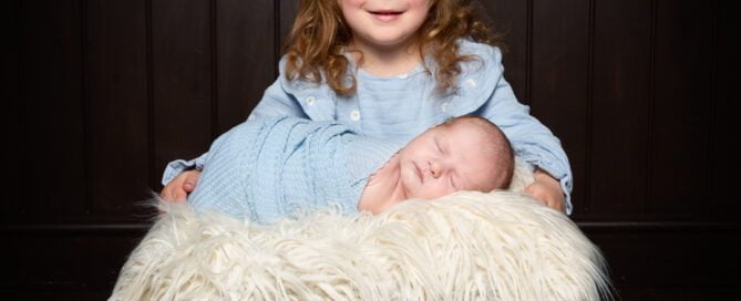 a newborn and big sister in matching shades of blue