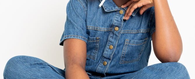 A girl in a denim jumpsuit sitting on top of a footstool