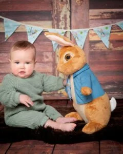 a baby and a large Peter Rabbit Toy