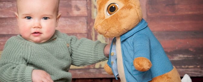a baby and a large Peter Rabbit Toy