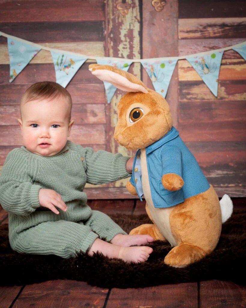 a baby and a large Peter Rabbit Toy