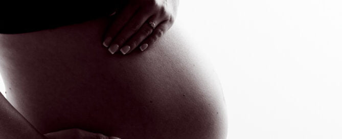 A pregnant belly in a black and white image against a white background