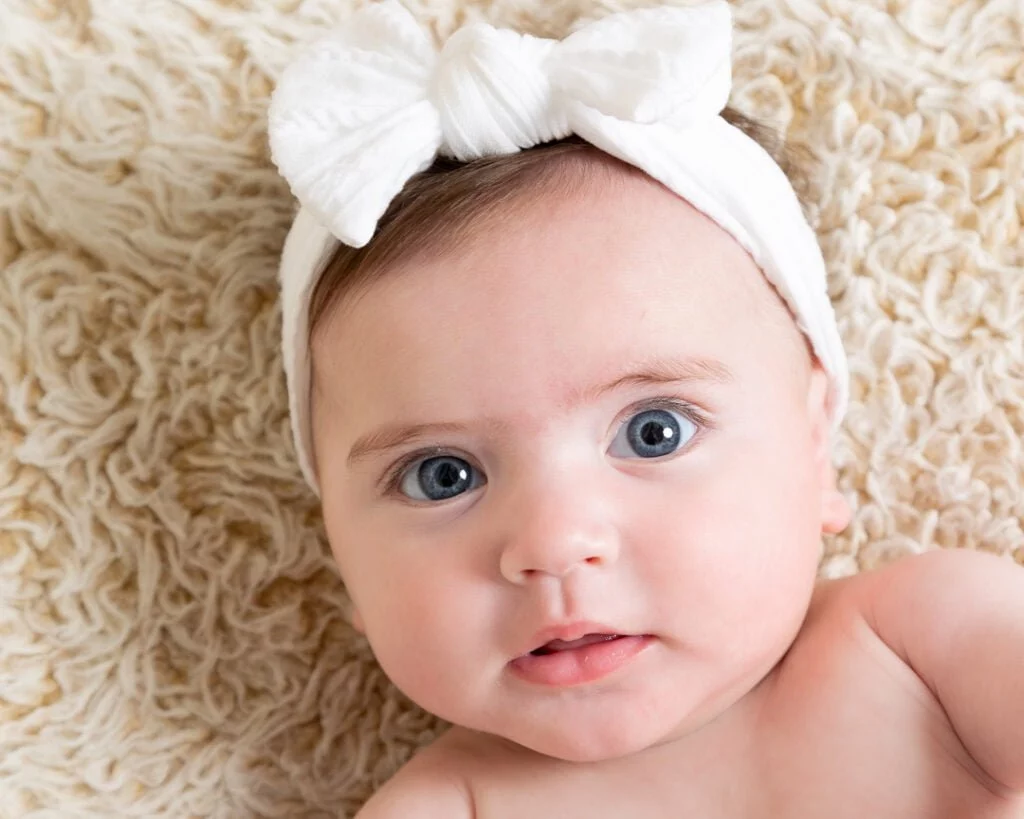 a little girl in a white headband looks at the camera