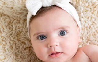 a little girl in a white headband looks at the camera