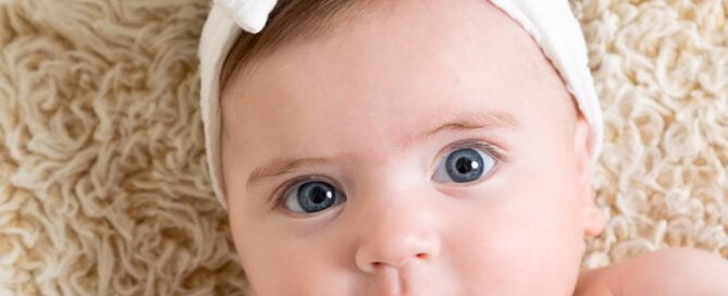 a little girl in a white headband looks at the camera