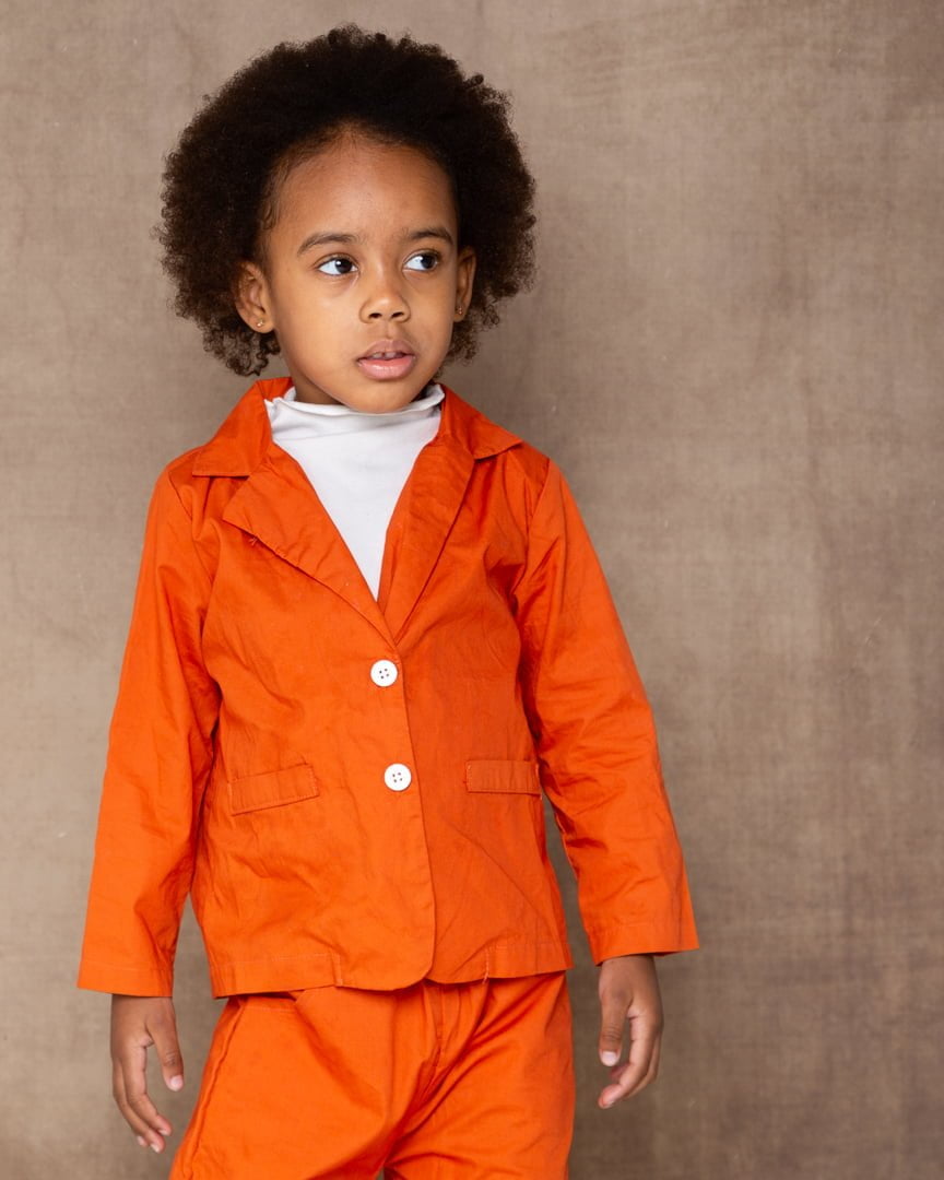a young girl poses in an orange outfit
