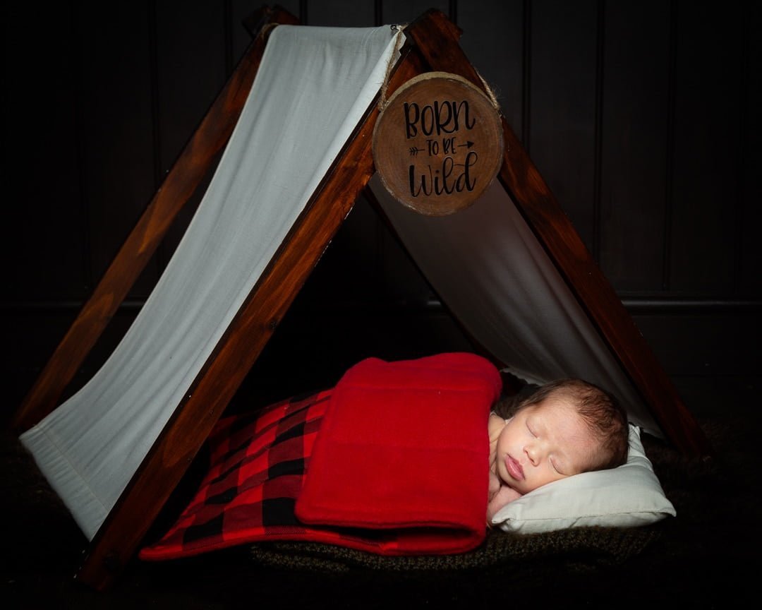 a newborn sleeping in my happy camper tent themed prop set