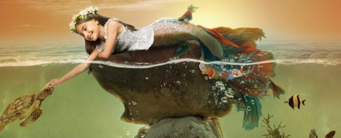 a little girl at a mermaid photo shoot reaching into the ocean