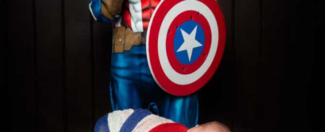 a little boy dressed as Captain America poses with his newborn brother wrapped in red, white and blue