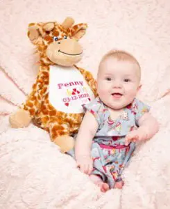 a baby sits with a personalised giraffe toy